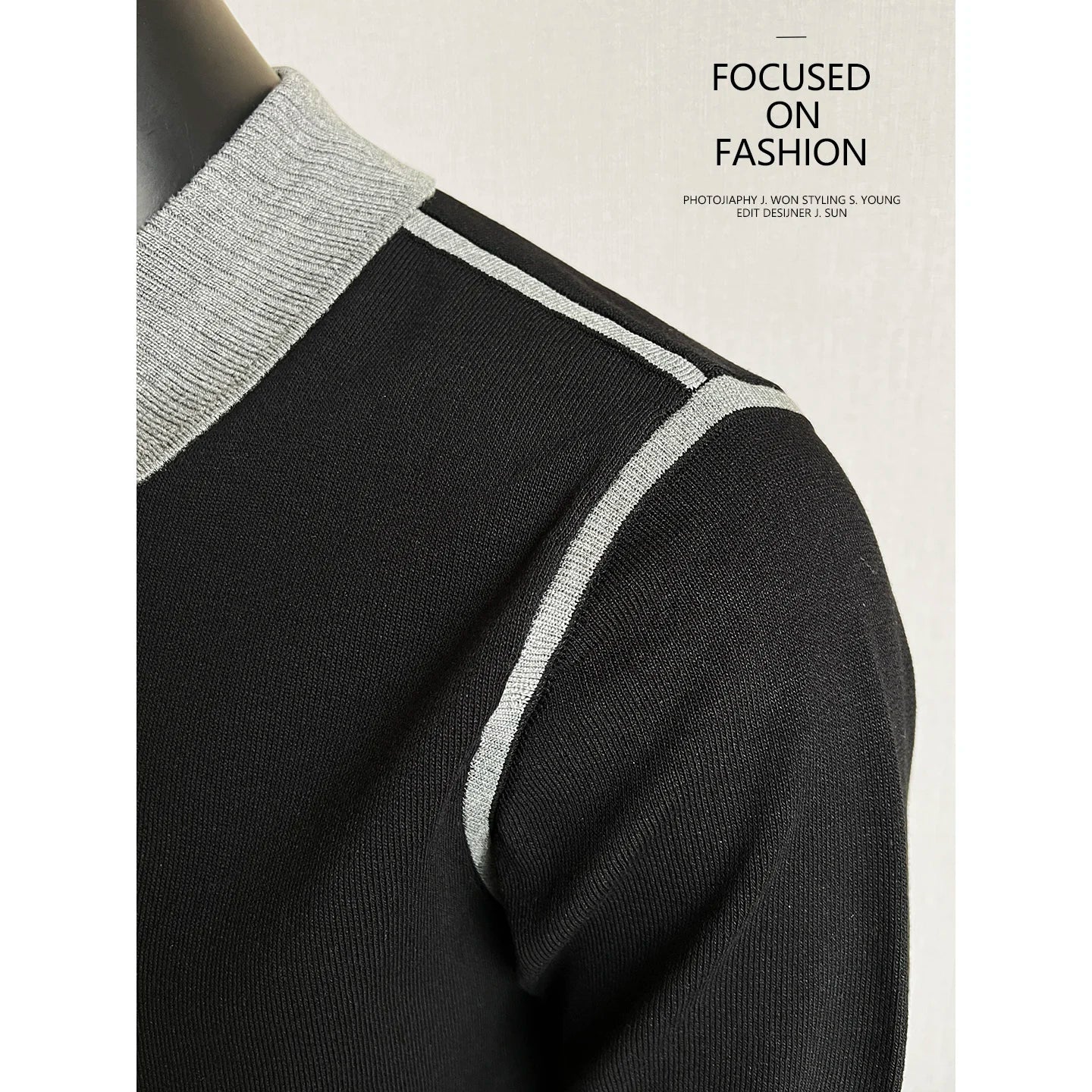 Close-up of gray shoulder piping on a black knit polo