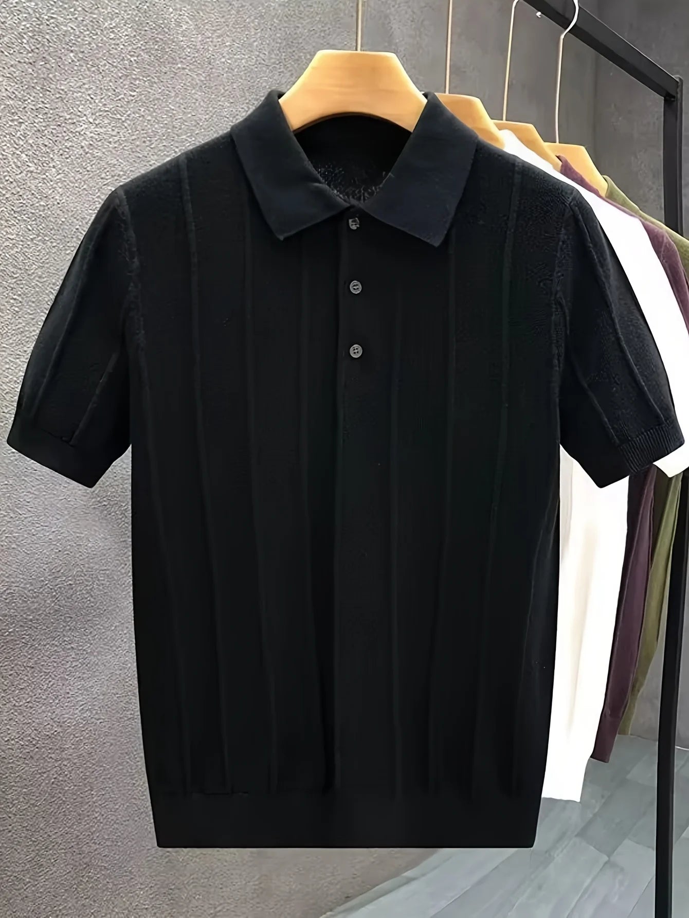 Black textured knit polo displayed on a hanger