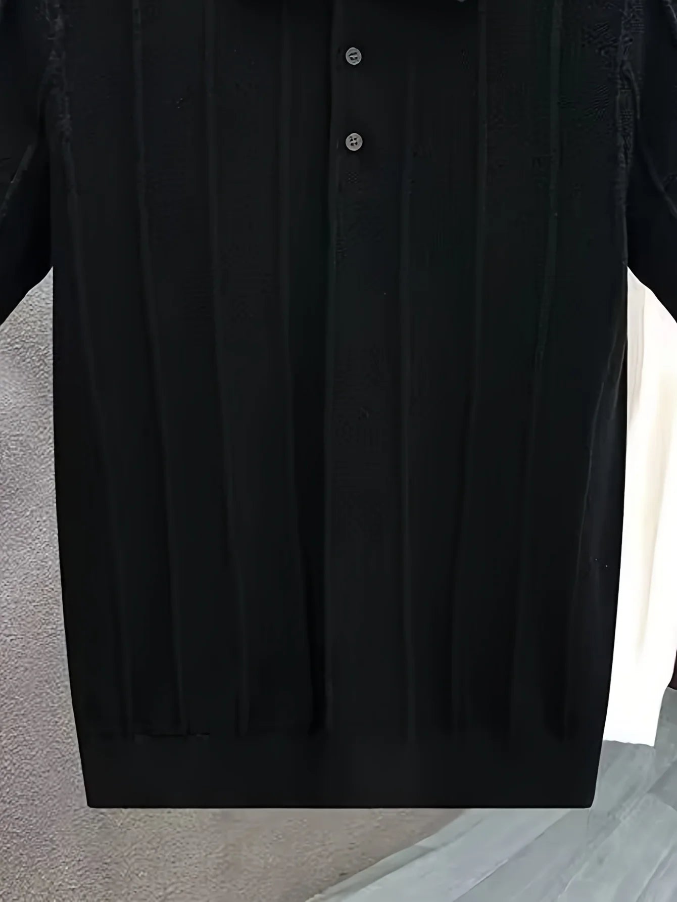 Close-up of the black polo button placket and vertical texture